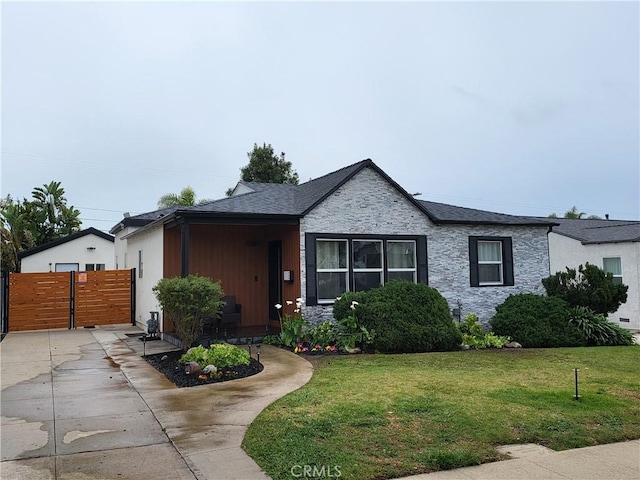 view of front facade featuring a gate, fence, a front lawn, and roof with shingles