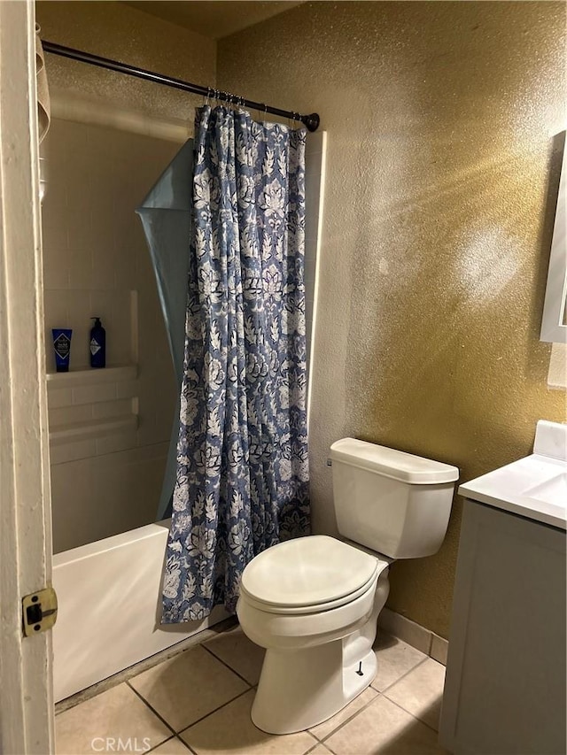 full bath featuring toilet, tile patterned flooring, baseboards, and a textured wall