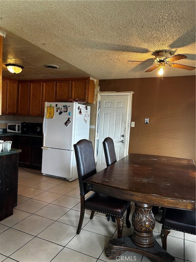 dining room featuring light tile patterned floors, ceiling fan, and a textured ceiling