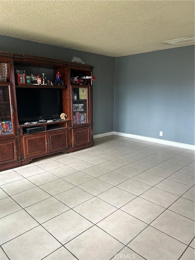 unfurnished living room with baseboards, a textured ceiling, and light tile patterned flooring