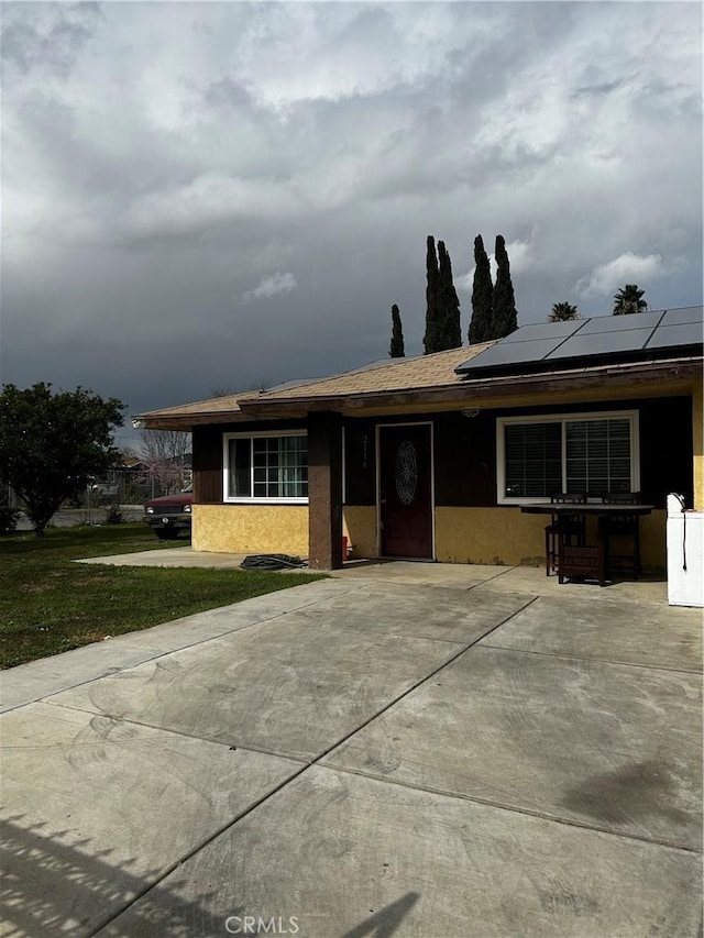 single story home with roof mounted solar panels and stucco siding