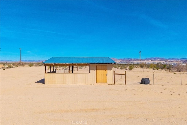 exterior space with view of desert, a mountain view, and an outbuilding