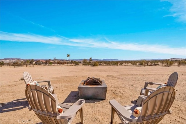 view of yard featuring a mountain view, a fire pit, a desert view, and a rural view