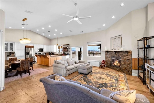 living room with recessed lighting, ceiling fan, high vaulted ceiling, and a stone fireplace