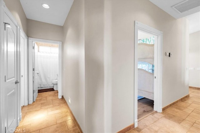 corridor with visible vents, recessed lighting, stone tile flooring, and baseboards