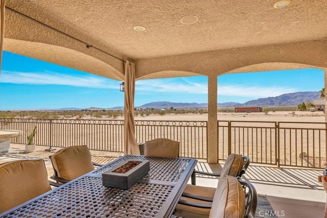 view of patio / terrace with outdoor dining area, a mountain view, and a fire pit