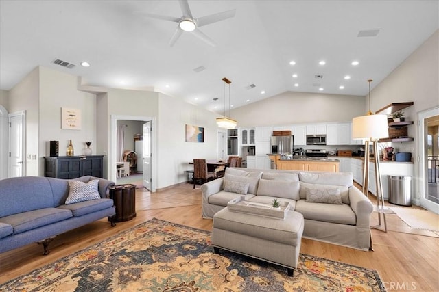 living room featuring high vaulted ceiling, light wood-style flooring, visible vents, and recessed lighting