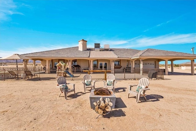 rear view of house with an outdoor fire pit, a patio area, fence, and a chimney