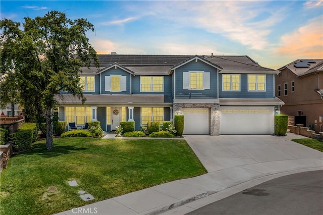 view of front of property with driveway, a yard, an attached garage, and a tiled roof