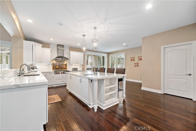 kitchen featuring stainless steel gas cooktop, light countertops, a sink, and wall chimney exhaust hood