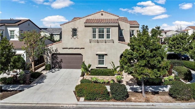 mediterranean / spanish home featuring a garage, driveway, a tiled roof, and stucco siding