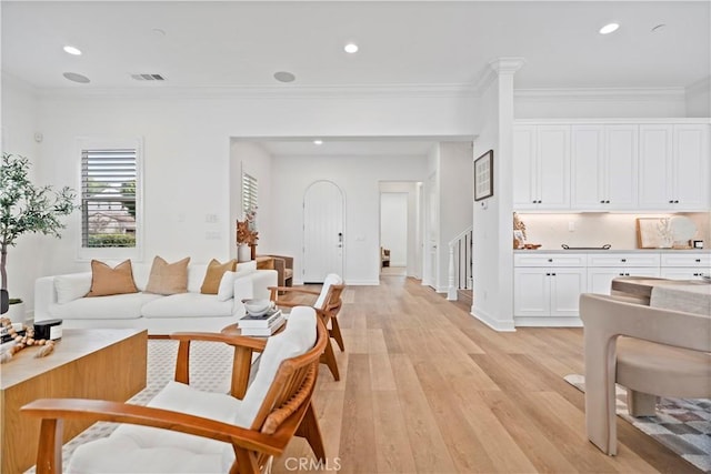 living area featuring light wood-style flooring, visible vents, crown molding, and recessed lighting