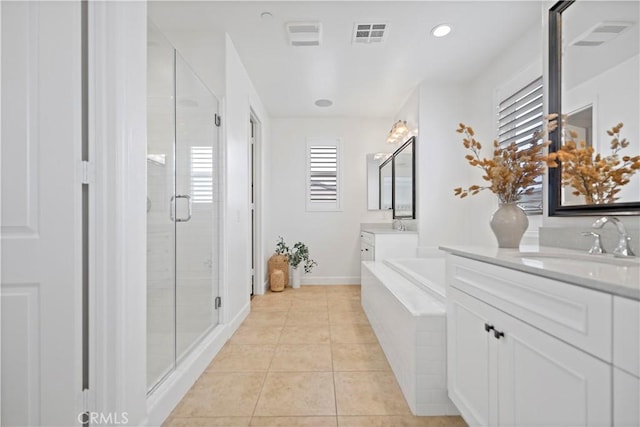 full bath with a garden tub, two vanities, a sink, a shower stall, and tile patterned floors