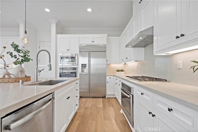 kitchen featuring crown molding, ventilation hood, light countertops, a sink, and built in appliances