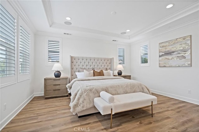 bedroom with a raised ceiling, multiple windows, and ornamental molding