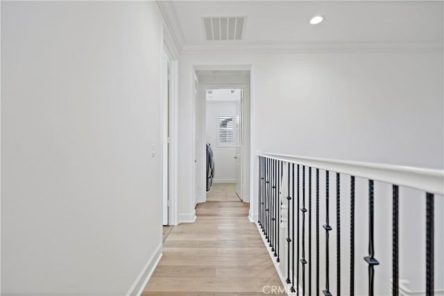 hallway featuring baseboards, visible vents, crown molding, light wood-type flooring, and recessed lighting