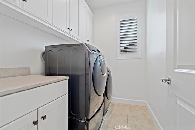 laundry area with washing machine and dryer, cabinet space, baseboards, and light tile patterned flooring