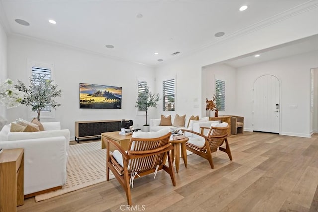 living room with light wood-style floors, ornamental molding, and a wealth of natural light