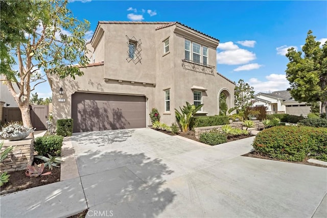 mediterranean / spanish-style home with driveway, an attached garage, fence, and stucco siding