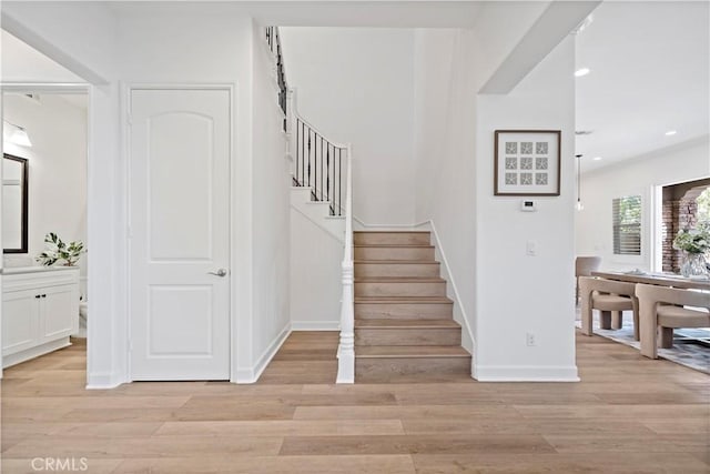 stairway featuring baseboards, wood finished floors, and recessed lighting