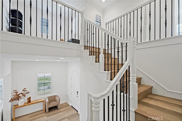 staircase with wood finished floors and crown molding