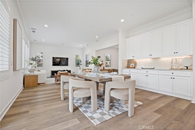 dining room featuring crown molding, a wealth of natural light, light wood-type flooring, and recessed lighting