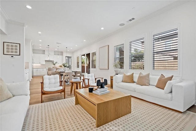 living room with ornamental molding, light wood-type flooring, visible vents, and recessed lighting