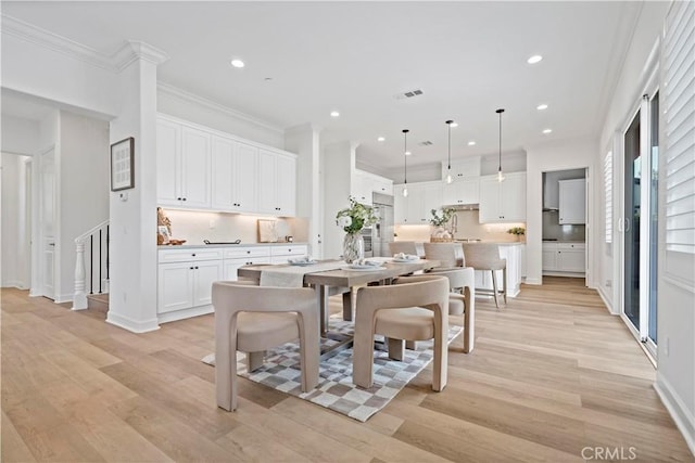 dining area featuring light wood finished floors, recessed lighting, visible vents, and crown molding