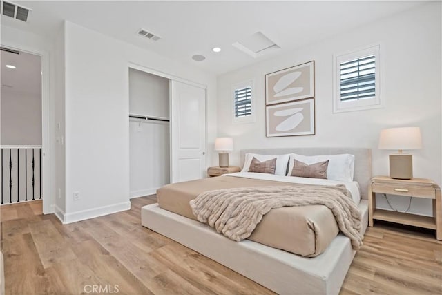 bedroom featuring light wood finished floors, visible vents, and a closet