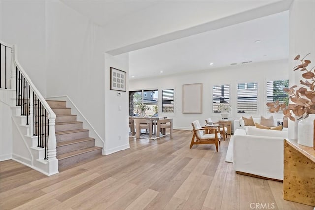 living area with recessed lighting, baseboards, stairway, and light wood finished floors