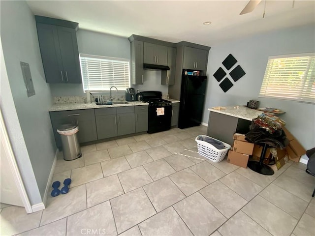 kitchen featuring black appliances, baseboards, under cabinet range hood, and a sink