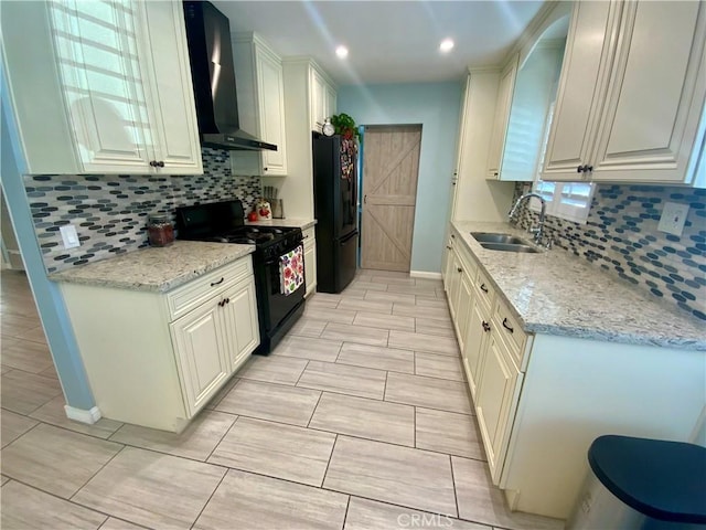kitchen featuring black appliances, a sink, tasteful backsplash, wall chimney range hood, and light stone countertops