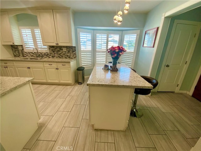 kitchen with a sink, wood finish floors, tasteful backsplash, and white cabinets