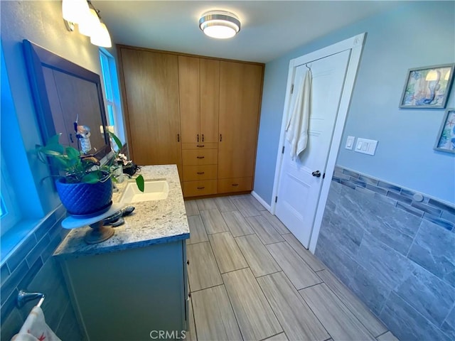 bathroom with wood tiled floor, tile walls, and vanity