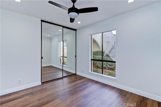 unfurnished bedroom with recessed lighting, a closet, ceiling fan, wood finished floors, and baseboards