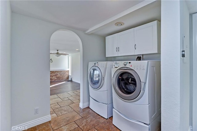 laundry area featuring cabinet space, arched walkways, ceiling fan, independent washer and dryer, and stone tile flooring