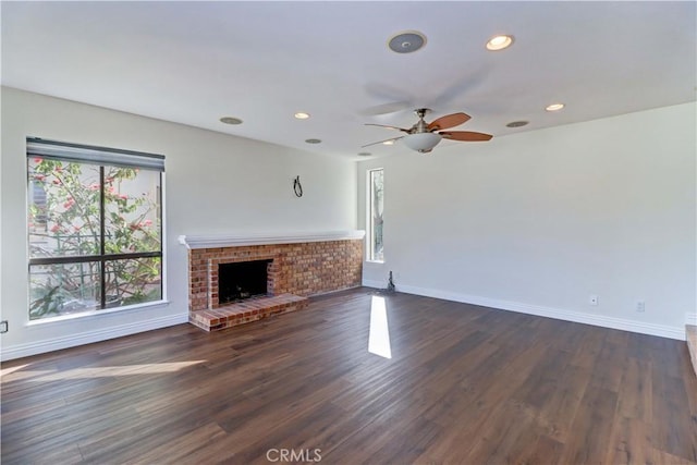 unfurnished living room with a brick fireplace, dark wood-style flooring, baseboards, and recessed lighting