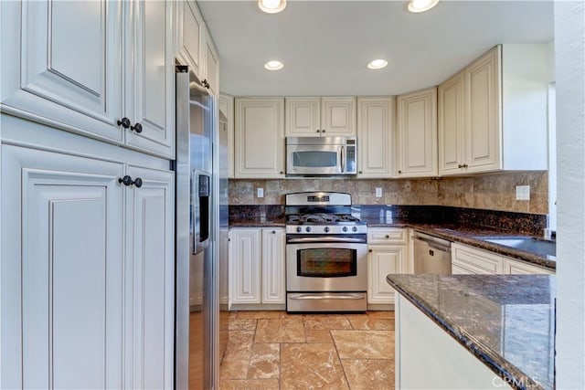 kitchen with tasteful backsplash, stone tile floors, dark stone counters, stainless steel appliances, and recessed lighting