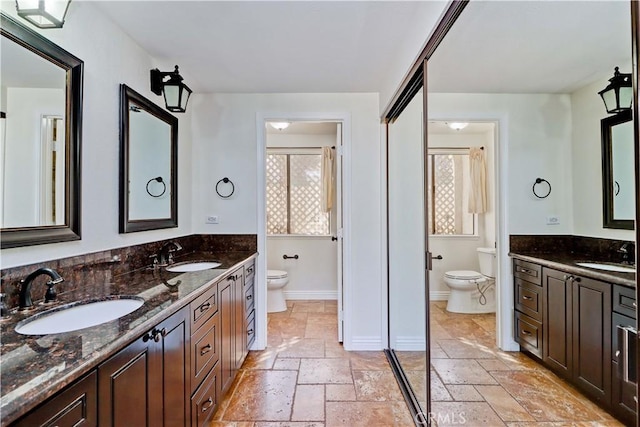 full bathroom with a sink, toilet, and stone tile floors