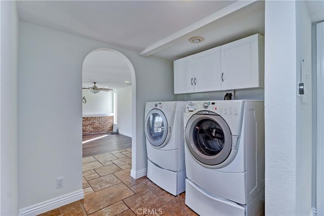 clothes washing area featuring arched walkways, washer and clothes dryer, cabinet space, stone finish flooring, and ceiling fan