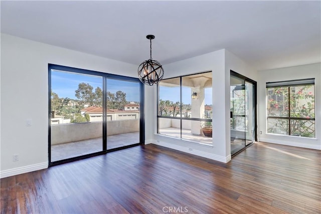 unfurnished dining area with a chandelier, plenty of natural light, and wood finished floors