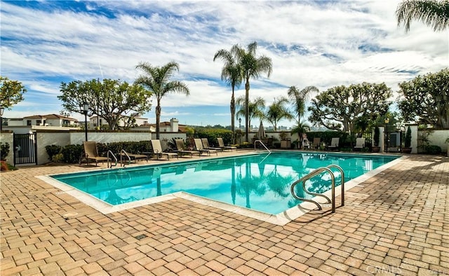 pool with a patio area and fence