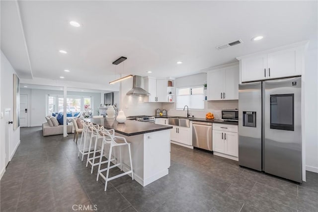 kitchen featuring open shelves, stainless steel appliances, dark countertops, a sink, and wall chimney exhaust hood