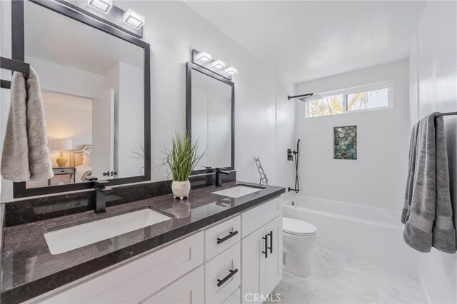 bathroom with shower / bathtub combination, double vanity, a sink, and toilet