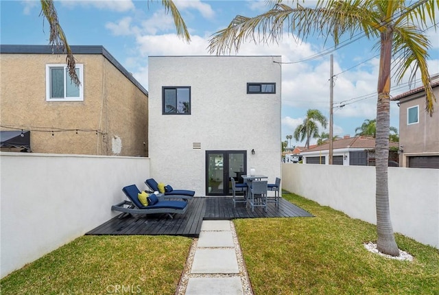 back of house with fence private yard, a lawn, a wooden deck, and stucco siding