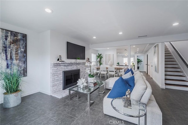 tiled living room with stairs, a brick fireplace, and recessed lighting