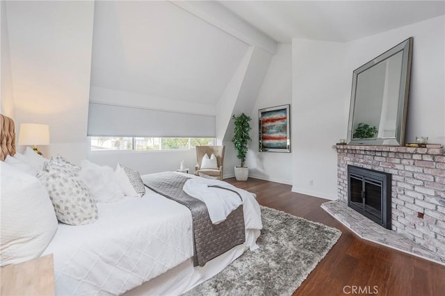 bedroom featuring vaulted ceiling with beams, a fireplace, wood finished floors, and baseboards