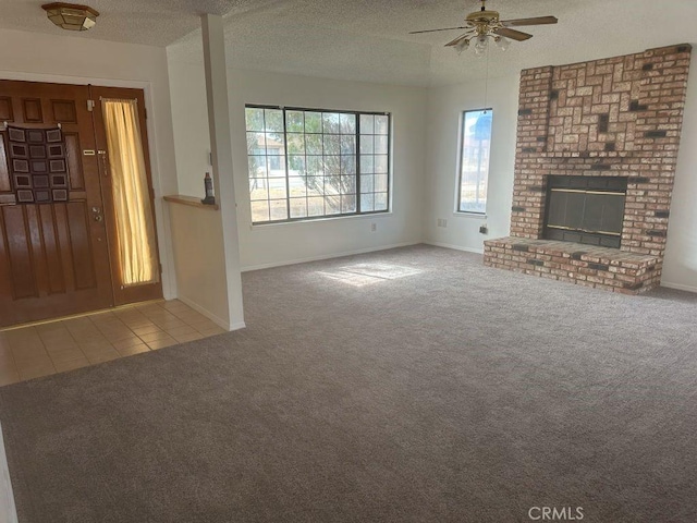 unfurnished living room with a textured ceiling, a fireplace, baseboards, tile patterned floors, and carpet