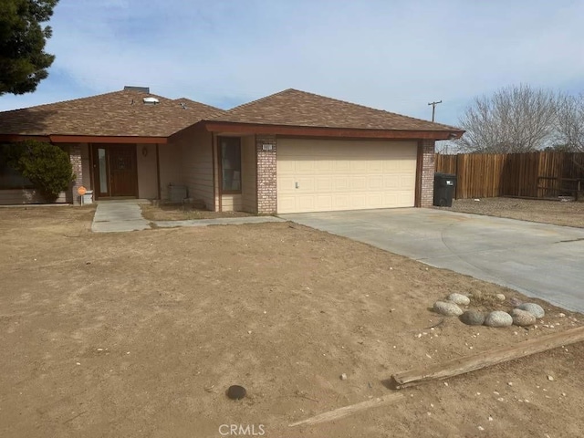 ranch-style home with a garage, concrete driveway, brick siding, and fence