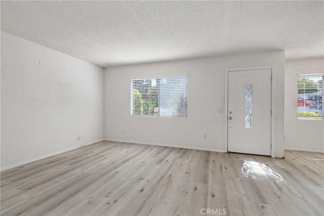 foyer featuring baseboards, a textured ceiling, and wood finished floors